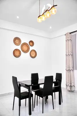 a dining room with a black table and chairs at Diamond Apartments in Arusha