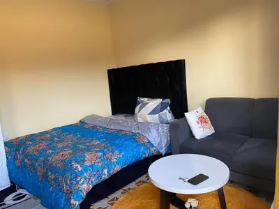 a bedroom with a bed and a couch and a table at Maasaifari Osmlai in Arusha