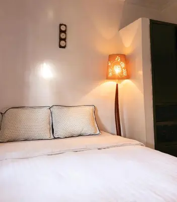 a bedroom with a bed with a lamp next to it at Kobe Nature Homestay in Arusha