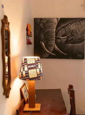 a lamp on a table next to a picture of an elephant at Kobe Nature Homestay in Arusha
