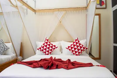 a bedroom with a bed with red and white pillows at Kigongoni Gazella Hotel in Mto wa Mbu