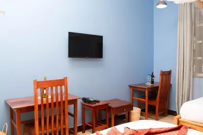 a living room with a table and a tv on the wall at Kigongoni Gazella Hotel in Mto wa Mbu