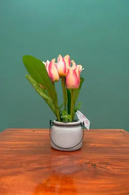 a white vase with pink flowers on a wooden table at Kigongoni Gazella Hotel in Mto wa Mbu