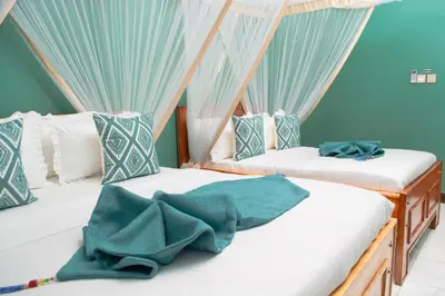 two beds in a room with blue curtains at Kigongoni Gazella Hotel in Mto wa Mbu
