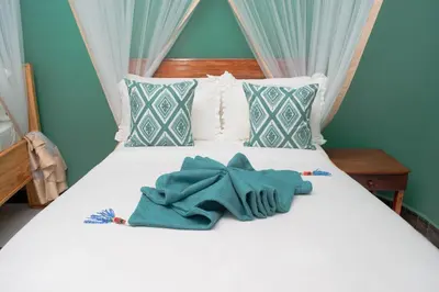 a white bed with a blue towel on it at Kigongoni Gazella Hotel in Mto wa Mbu