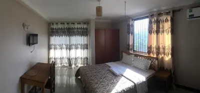 a bedroom with a bed and a desk and windows at maasaifari runako in Ilboru