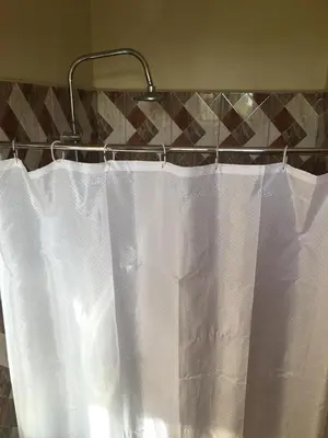 a white shower curtain hanging on a towel rack at maasaifari runako in Ilboru