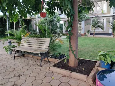 a wooden bench sitting under a tree in a yard at Luxury 2BR apartment in Usa River