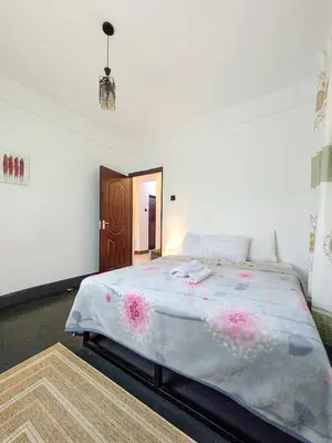 a bedroom with a large bed with pink flowers on it at Fly Africa Village in Arusha