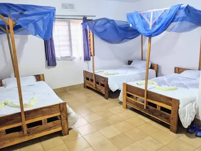 three beds in a room with blue umbrellas at Domus Aurea Safaris in Oldeani