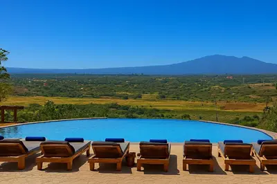a group of chairs sitting next to a swimming pool at Mamadunia Safari Lodge in Karatu