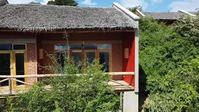 a small red house with a thatched roof at Mamadunia Safari Lodge in Karatu