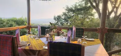 a table set up for a meal on a porch at Mamadunia Safari Lodge in Karatu
