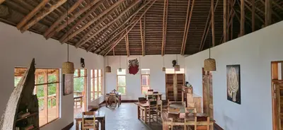 a room with wooden ceilings and tables and chairs at Mamadunia Safari Lodge in Karatu