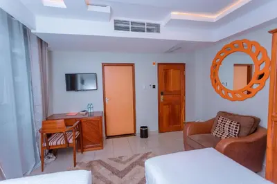 a room with a bed and a desk and a mirror at Selig Hotel in Moshi