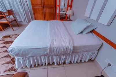 a bed with white sheets and pillows in a room at Selig Hotel in Moshi