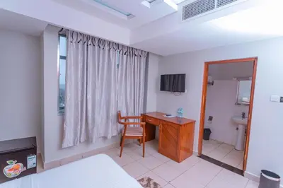 a bedroom with a desk and a bed and a bathroom at Selig Hotel in Moshi