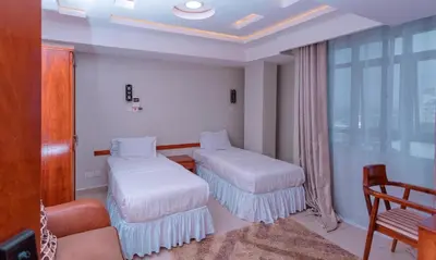 a hotel room with two beds and a couch at Selig Hotel in Moshi