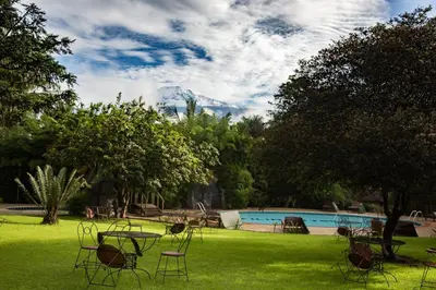 a yard with chairs and a pool with a mountain at KILEMAKYARO Mt LODGE in Uru