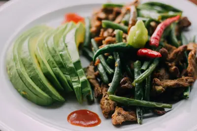 a plate of food with meat and green beans and vegetables at KILEMAKYARO Mt LODGE in Uru