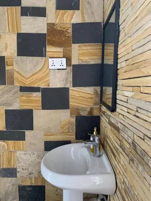 a bathroom with a sink and a tile wall at Peakline Apartments in Arusha