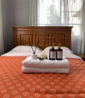 a bed with two bottles of whiskey and flowers on it at Peakline Apartments in Arusha