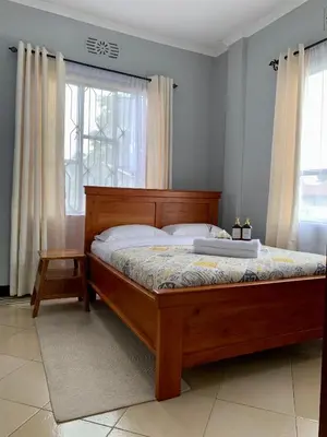 a bedroom with a bed with a wooden frame and a window at Peakline Apartments in Arusha