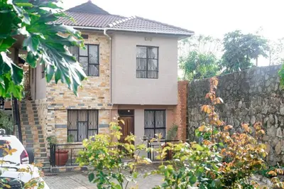 a house with a stone wall and a fence at Peakline Apartments in Arusha
