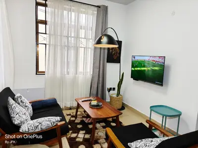 a living room with a couch and a tv on a wall at Twiga Luxe in Arusha