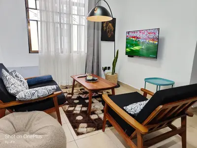 a living room with chairs and a tv on the wall at Twiga Luxe in Arusha
