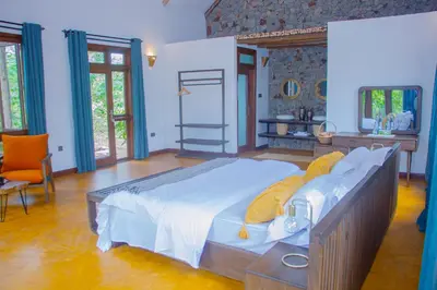 a bedroom with a large bed with yellow pillows at Moonbow lodge in Mto wa Mbu