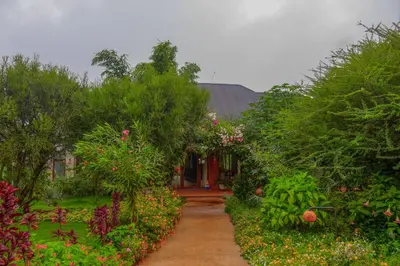 a house with a garden with flowers and trees at Moonbow lodge in Mto wa Mbu
