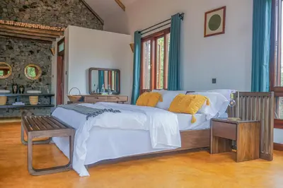 a bedroom with a bed with a bench and a mirror at Moonbow lodge in Mto wa Mbu