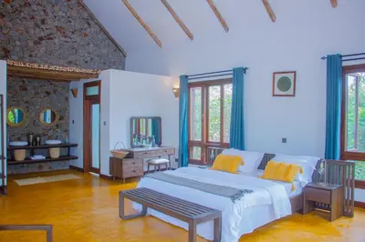 a bedroom with a large white bed and a table at Moonbow lodge in Mto wa Mbu