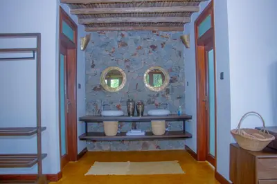 a bathroom with two sinks and two mirrors on the wall at Moonbow lodge in Mto wa Mbu