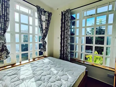 a bedroom with two large windows and a bed at Garden View with detached Bathroom in Arusha