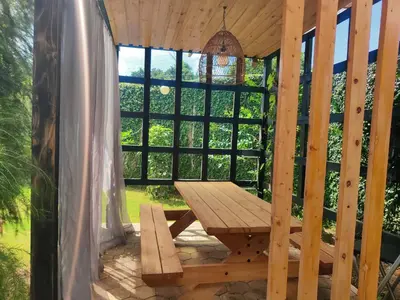 a wooden picnic table on a porch with a large window at Garden View with detached Bathroom in Arusha