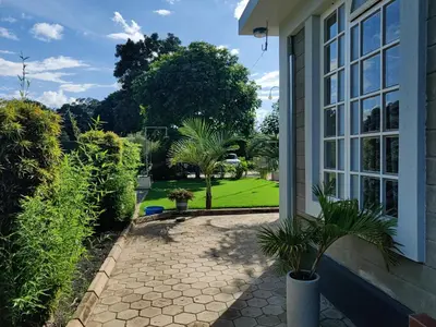 a porch of a house with a courtyard with trees at Garden View with detached Bathroom in Arusha