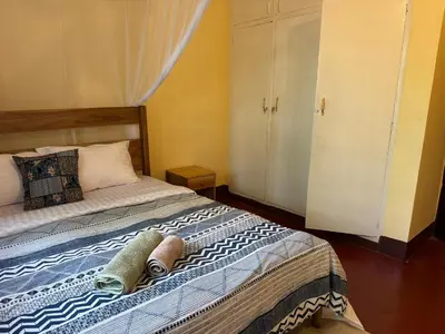 a bedroom with a bed and a white cabinet at Mahali House in Moshi