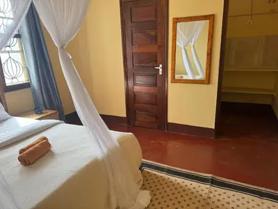 a bedroom with a bed and a mirror and a door at Mahali House in Moshi