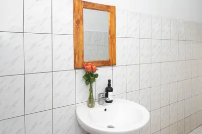 a bathroom sink with a mirror and a vase with flowers at Mahali House in Moshi