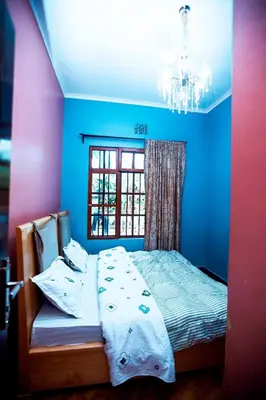 a bedroom with a bed with blue walls and a window at Bed and Stay with Mount Kilimanjaro View in Moshi