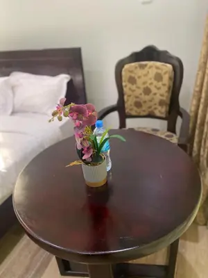 a wooden table with a vase of flowers on it at Serene Vacay Hotel Marangu in Marangu