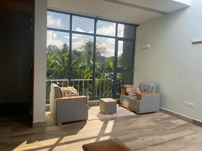 a living room with two chairs and a large window at Serene Vacay Hotel Marangu in Marangu