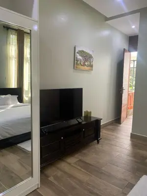a bedroom with a bed and a flat screen tv at Serene Vacay Hotel Marangu in Marangu