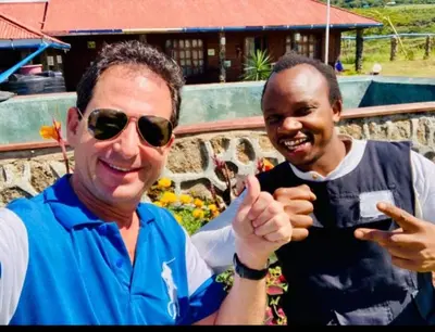 two men standing next to each other giving a thumbs up at Eco Farm in Karatu