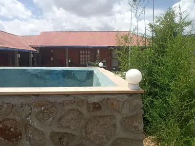 a swimming pool in front of a brick building at Eco Farm in Karatu