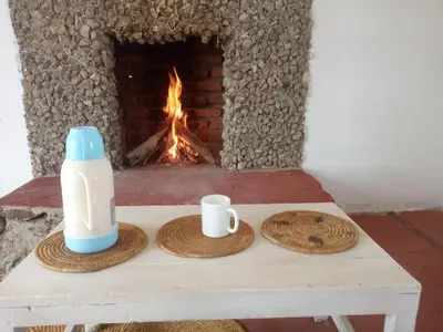 a table with two cups and a bottle of milk and a fireplace at Eco Farm in Karatu