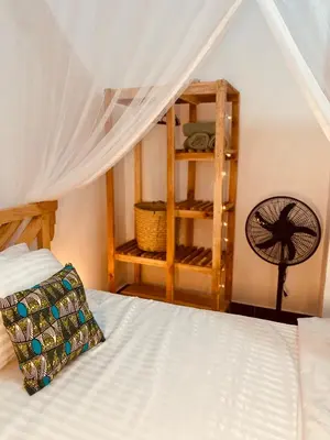 a bedroom with a white bed and a fan at Tukutane Kilimanjaro - Homestay in Uru