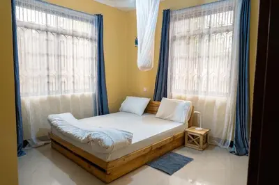 a small bed in a room with two windows at Tukutane Kilimanjaro - Homestay in Uru